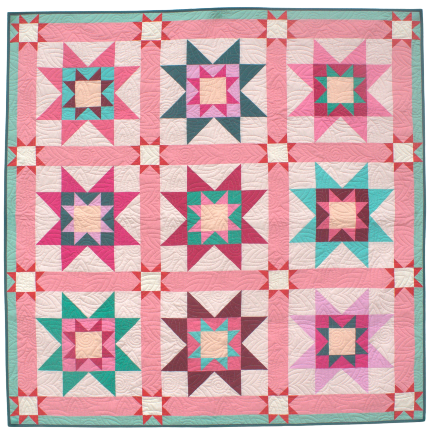 Quilt with star pattern in pink, green, and white on a blue background