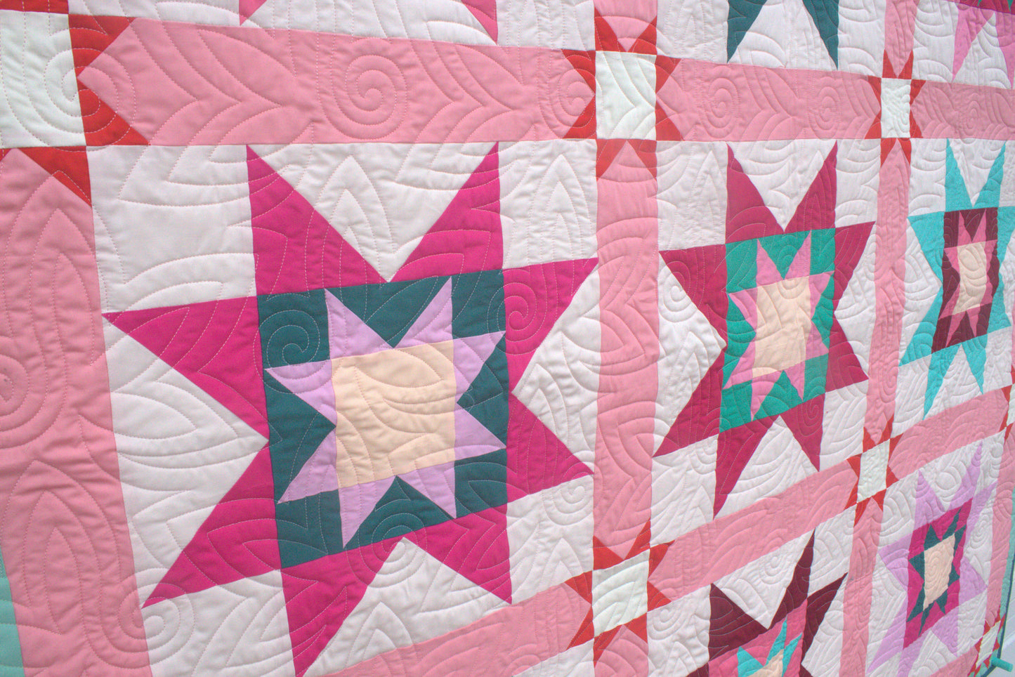 Quilt with star pattern in pink, green, and white