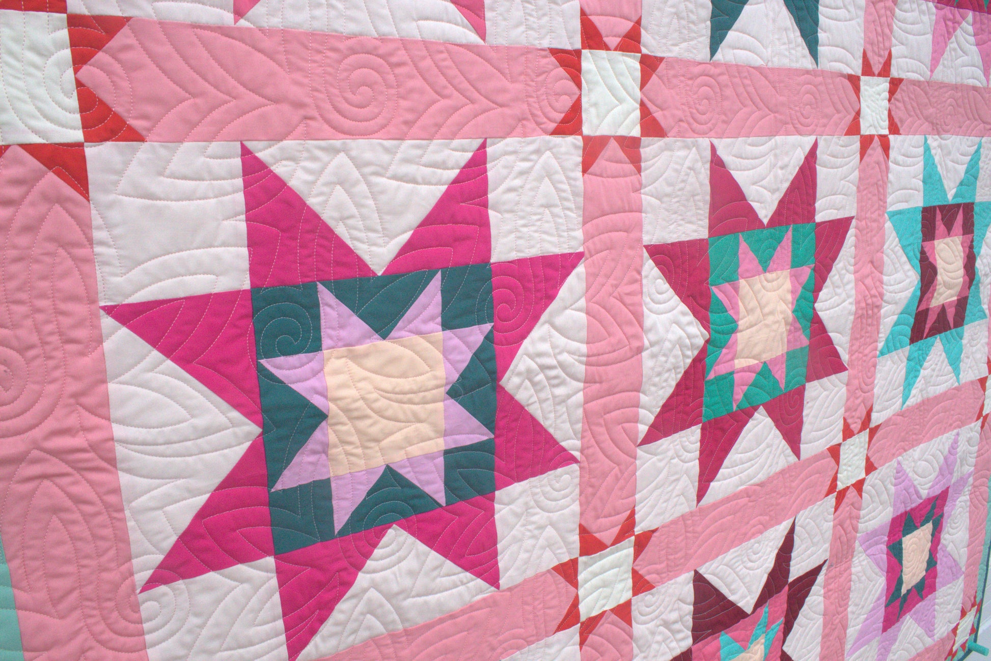 Quilt with star pattern in pink, green, and white